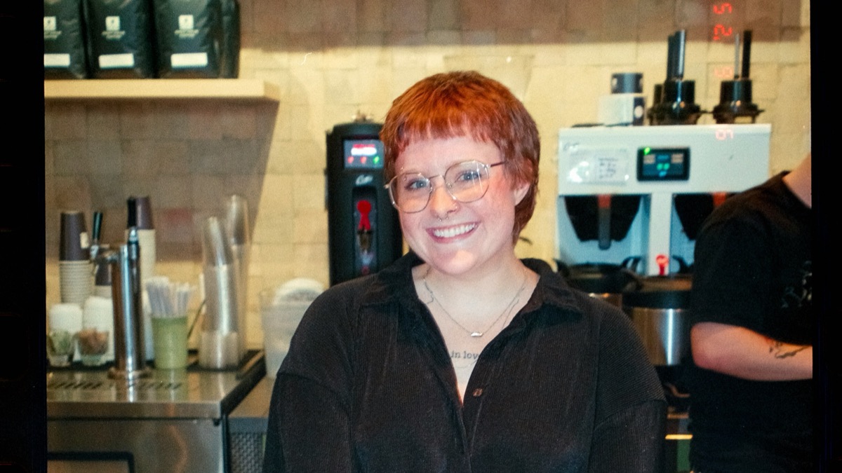 Coffee shop counter with a digital loyalty card displayed on a smartphone next to a takeaway cup