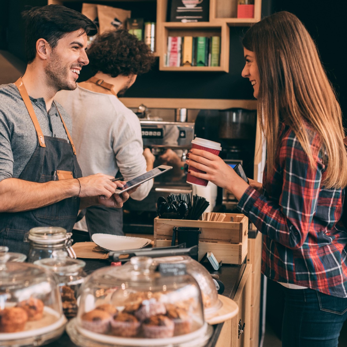 Barista scanning customer phone at coffee shop counter