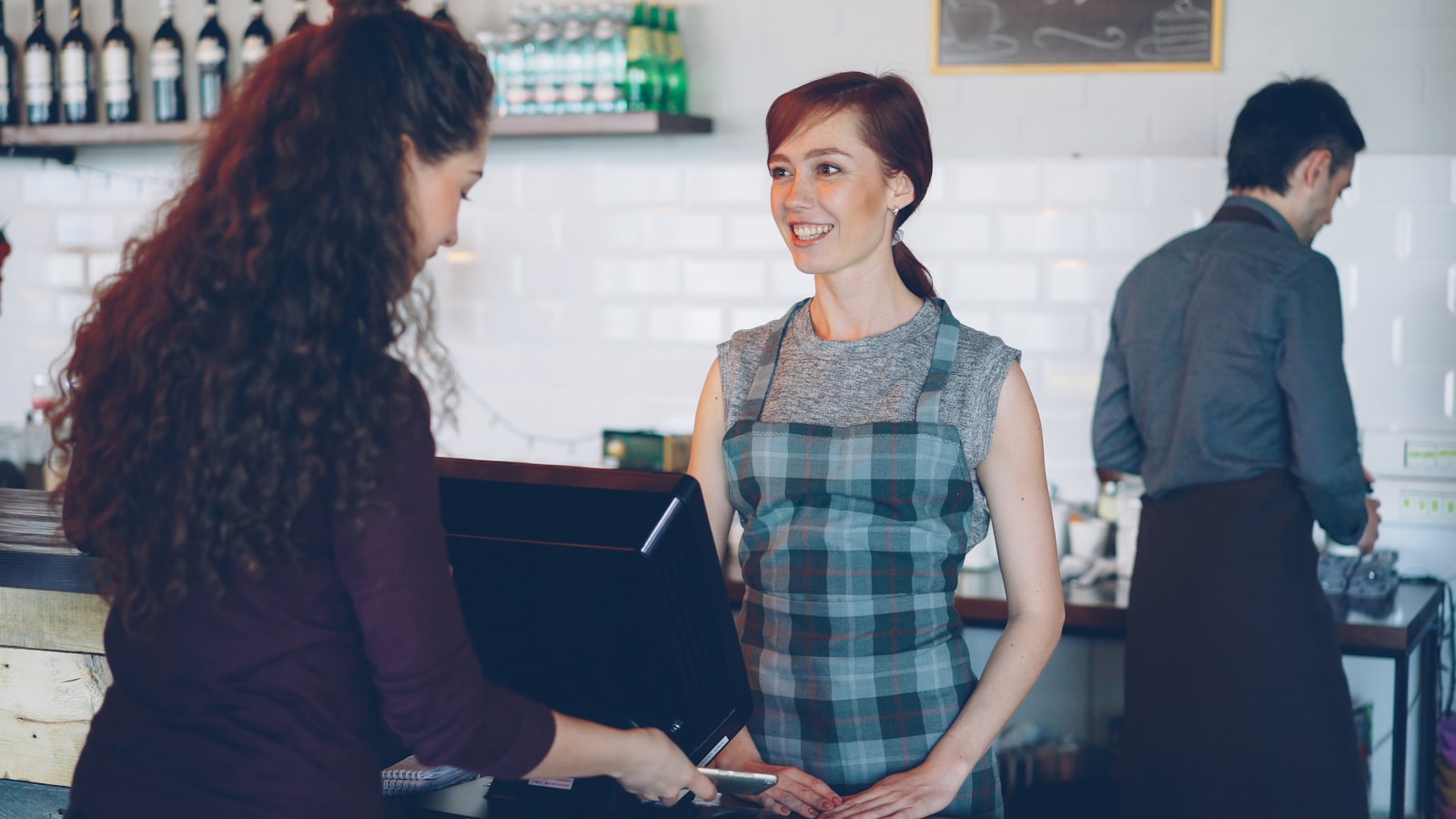 Personal de una cafetería atendiendo y cobrando a un cliente en el mostrador, un buen momento para invitarle a dejar una reseña en Google.