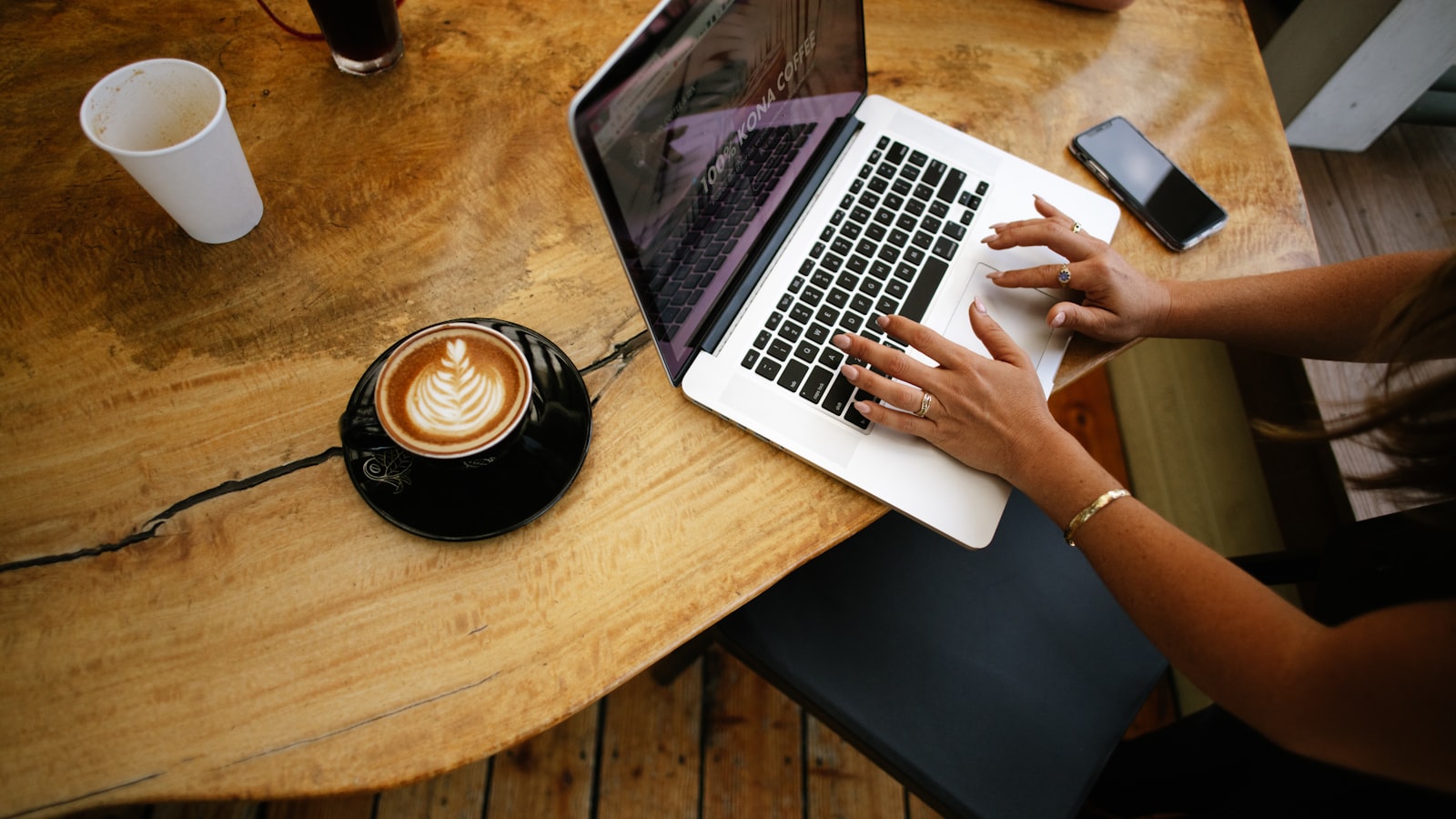 A business owner typing a calm reply to a review on a laptop beside a cup of coffee
