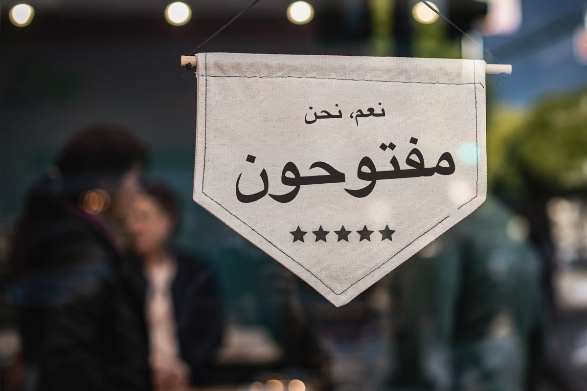 لافتة قماشية «نعم، نحن مفتوحون» معلّقة في واجهة متجر صغير مع إضاءة دافئة