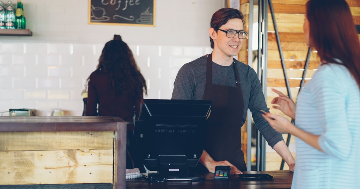 Customer paying at a small business coffee shop counter — loyalty programme at checkout