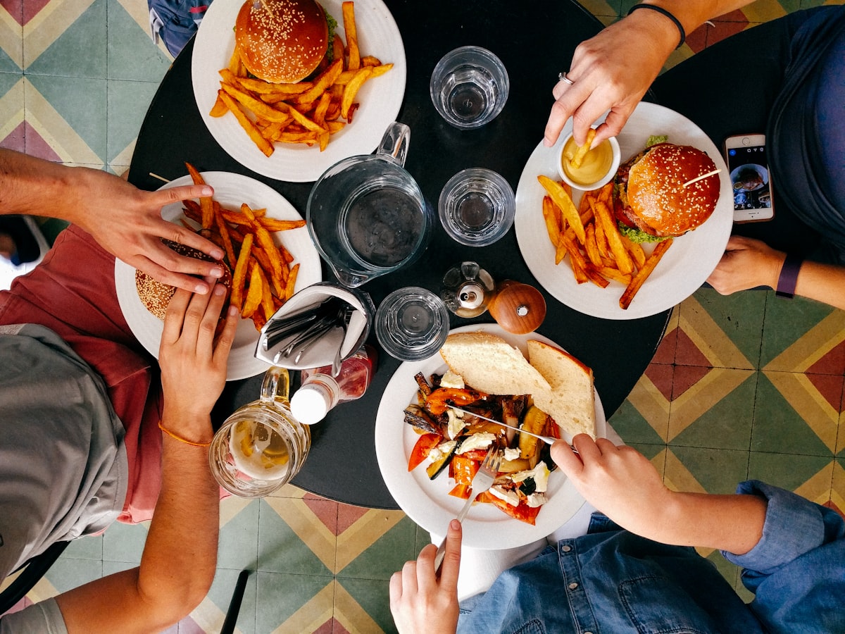 Friends eating burgers and fries at a restaurant table, top-down view