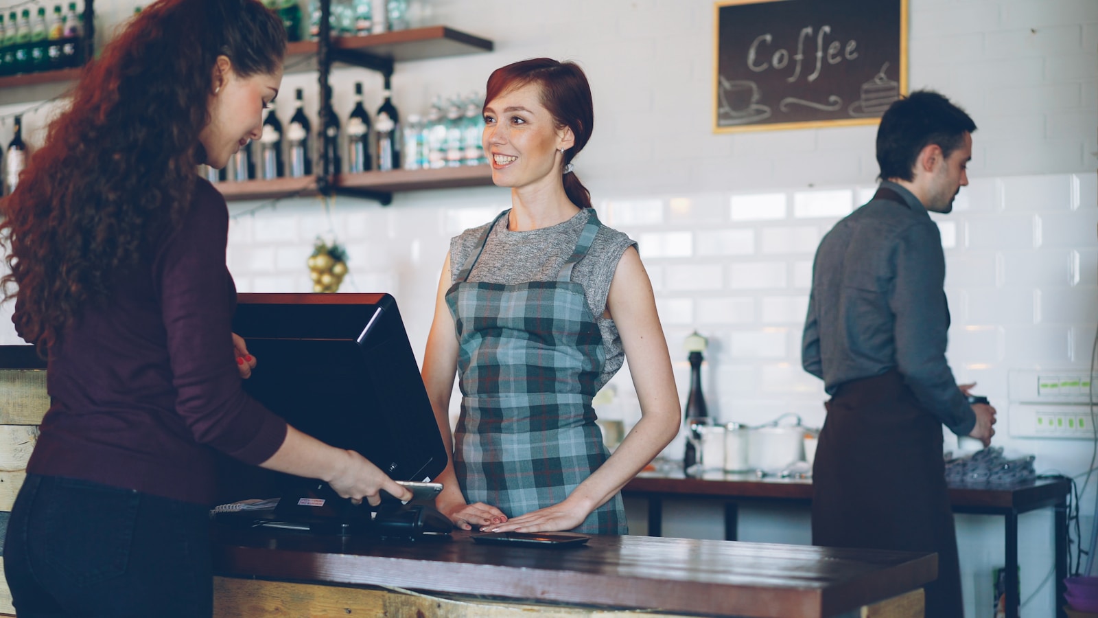 Customer paying at a cafe counter with a smartphone — replacing paper loyalty cards with a digital one