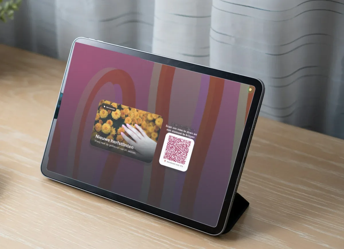 Illustratie: een iPad op een licht houten bureau met een nagelstudio-actie "New autumn shades" en een QR-code om mee te doen en een stempel te halen.